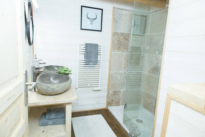 Treehouse bathroom with twin stone sinks and shower at at Château de Memanat in Creuse