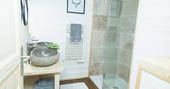 Treehouse bathroom with twin stone sinks and shower at at Château de Memanat in Creuse