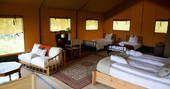 Inside of Meru with a king-size bed and single beds at Le Camp in France 