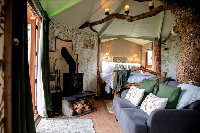 Living space has a sofa facing the view and a wood-burner beside