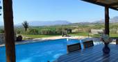View out from the covered terrace across the private pool to distant mountain landscape and Abruzzo countryside 