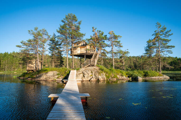 View from the wooden walkway across the river to Treetop Fiddan tree house in southern norway 