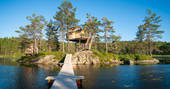 View from the wooden walkway across the river to Treetop Fiddan tree house in southern norway 