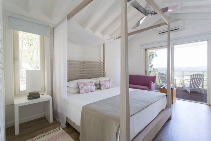 The light and airy bedroom of Camomila treehouse with king-size bed and doors opening out to stunning views across the valley