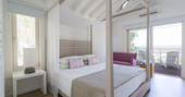 The light and airy bedroom of Camomila treehouse with king-size bed and doors opening out to stunning views across the valley