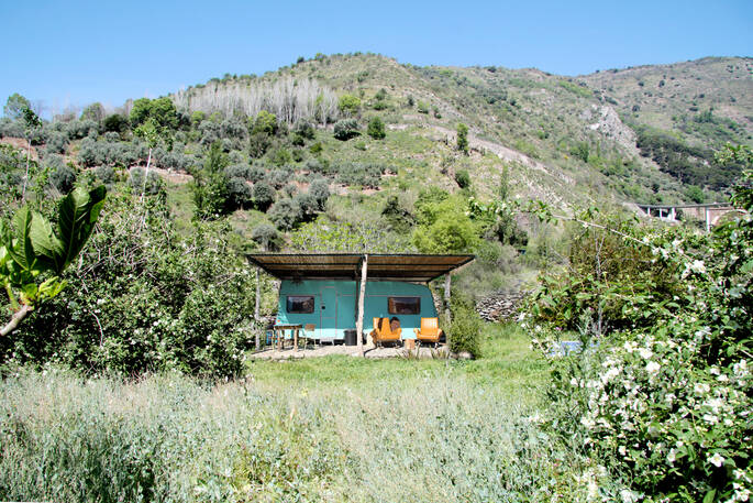 Bright blue La Caravana with orange seating area surrounded by nature at Casabayacas