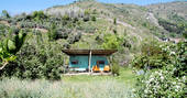 Bright blue La Caravana with orange seating area surrounded by nature at Casabayacas